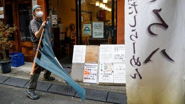 Sixty-year-old Yashiro Haga holds a curtain as he prepares for the opening of his ramen noodle shop Shirohachi in Tokyo on November 20. Unprecedented customer slump due to coronavirus outbreak is forcing Haga’s shop to close its doors after serving ramen to locals for fifteen years. (Issei Kato / Reuters)