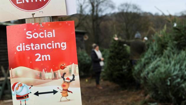 A social distancing sign is pictured as people visit a Christmas Tree Farm.(Reuters) A social distancing sign is pictured as people visit a Christmas Tree Farm.(Reuters)