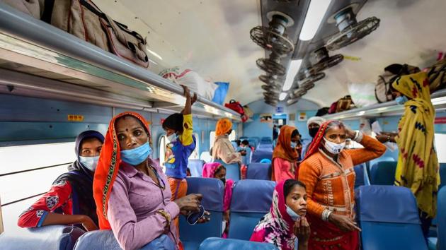 Passengers, wearing masks, board a train at Nizamuddin Railway Station in New Delhi.(PTI)