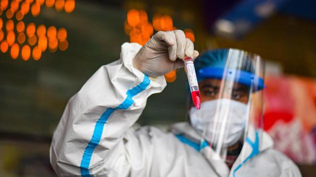 A health worker in PPE holds up a swab sample collected for coronavirus screening, at New Delhi Railway Station (NDLS), in New Delhi.(Amal KS/HT PHOTO) A health worker in PPE holds up a swab sample collected for coronavirus screening, at New Delhi Railway Station (NDLS), in New Delhi.(Amal KS/HT PHOTO)