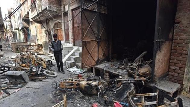 A man stands near burnt motorcycles in a riot-affected area, at Shiv Vihar, in New Delhi.(Sanchit Khanna/HT PHOTO)