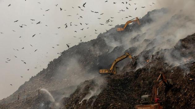 Firefighters and excavators try to douse fire as smoke billows from burning garbage at the Ghazipur landfill site in New Delhi.(REUTERS) Firefighters and excavators try to douse fire as smoke billows from burning garbage at the Ghazipur landfill site in New Delhi.(REUTERS)