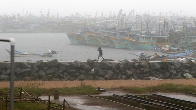 A man walks amid rain at the Kasimedu Harbor on the Bay of Bengal coast in Chennai on November 25. Tamil Nadu state authorities issued an alert and asked people living in low-lying and flood-prone areas to move to safer places.  (R Parthiban / AP) 