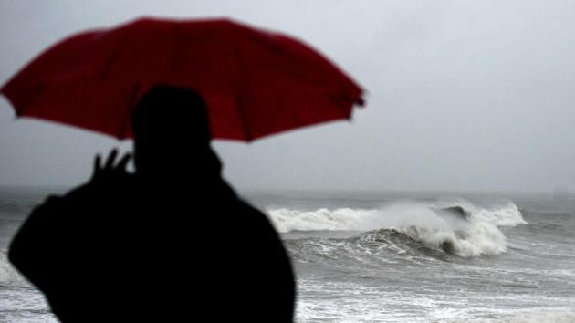 A man shelters under an umbrella from heavy rains while looking out to the Indian ocean as cyclone Nivar approaches the southeastern Indian coast in Puducherry on November 25, 2020. Several thousand people in south-eastern India fled their homes on November 25. (Arun Sankar / AFP) 