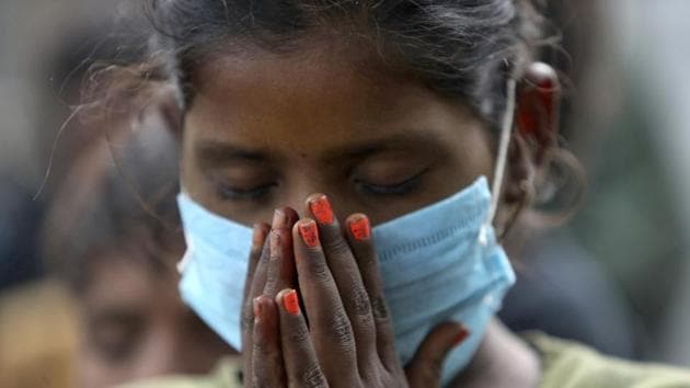 An underprivileged child wearing face mask as a precaution against the coronavirus participates in morning prayer at the Sangharsh Vidya Kendra school at a slum area on the outskirts of Jammu on Wednesday.(AP)