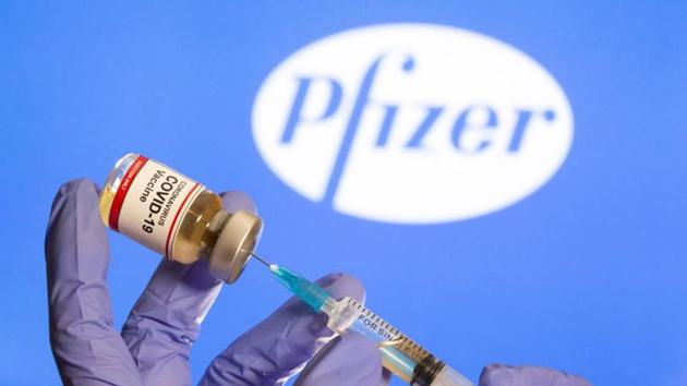 A woman holds a small bottle labeled with a "Coronavirus Covid-19 Vaccine" sticker and a medical syringe in front of displayed Pfizer logo.(Reuters) A woman holds a small bottle labeled with a "Coronavirus Covid-19 Vaccine" sticker and a medical syringe in front of displayed Pfizer logo.(Reuters)