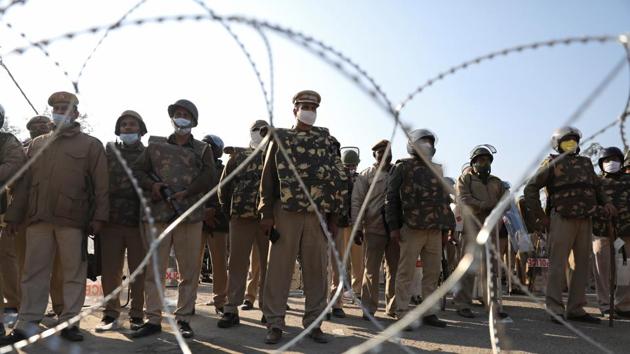 Police officers gather behind barbed wires to stop farmers opposing the newly passed farm bills from entering the national capital Delhi, at Singhu border, India, November 27, 2020.(REUTERS) Police officers gather behind barbed wires to stop farmers opposing the newly passed farm bills from entering the national capital Delhi, at Singhu border, India, November 27, 2020.(REUTERS)