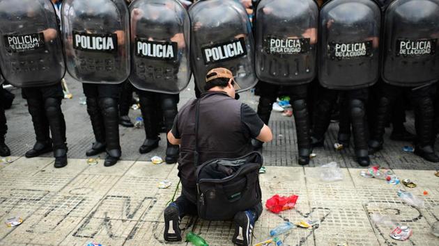 A man is seen on his knees as he argues with the police to enter the Government House to pay tribute to late football legend Diego Armando Maradona in Buenos Aires, Argentina on November 26. (Ronaldo Schemidt / AFP)