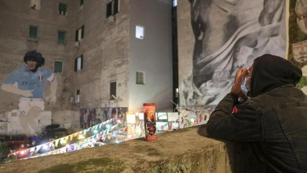 A man prays in front of a mural of Maradona in Naples, Italy on November 25. (Salvatore Laporta / AP)