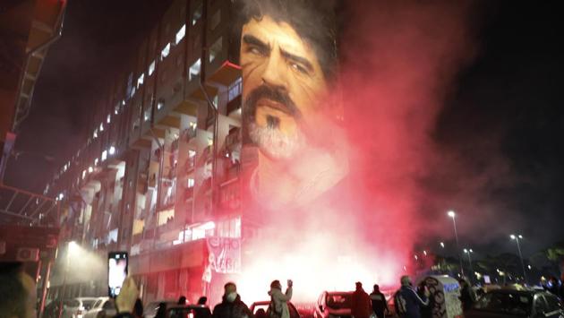 People gathered under a mural of Maradona light smoke torches in Naples, Italy on November 25. (Fabio Sasso / LaPresse via AP)