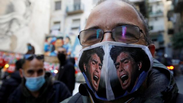 A man seen wearing a face mask with Maradona’s picture printed on it as people gather to mourn the football legend’s death in Naples, Italy on November 26. (Ciro De Luca / REUTERS)
