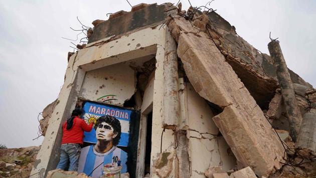 Syrian painter Aziz Asmar paints a portrait of Maradona on the wall of a destroyed home in Binnish, Syria on November 26. (Haj Kadour / AFP)
