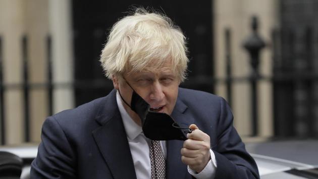 Britain's Prime minister Boris Johnson takes his face mask off as he returns to 10 Downing Street in London.(AP)