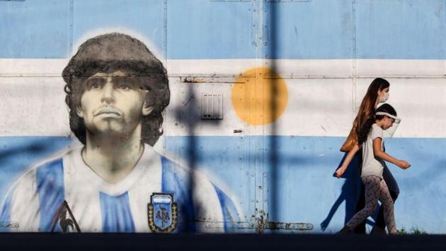 FILE PHOTO: People walk past a graffiti of soccer legend Diego Armando Maradona in Buenos Aires, Argentina.(REUTERS)