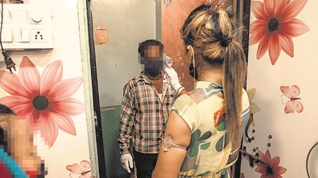 A sex worker performs thermal screening of a man before he enters her residence at red light area in Budhwar Peth.(Pratham Gokhale/HT Photo)
