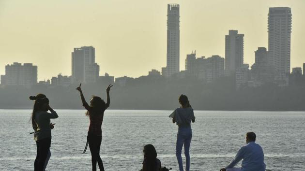 Mumbai: Youngsters enjoy the clear weather while a senior citizen practises yoga on the promenade at Marine Drive.(Anshuman Poyrekar/HT PHOTO)