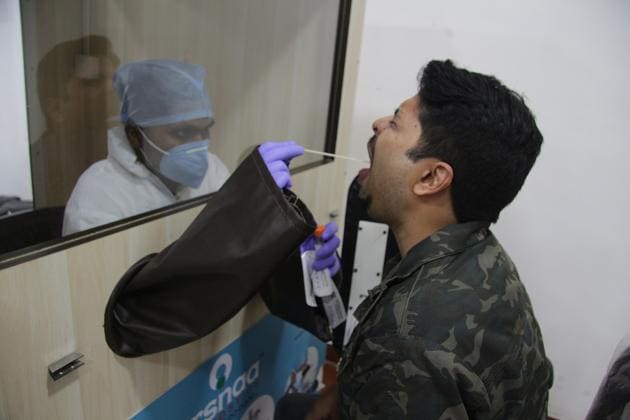 A healthcare worker collects swab samples from passengers at a Covid-19 testing centre at the Pune International Airport, on Saturday.(HT PHOTO)