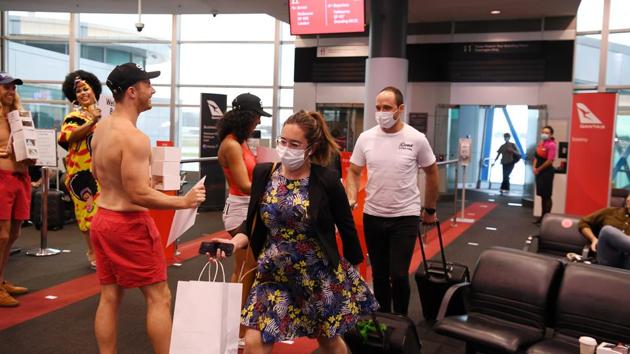 Passengers disembark from the first Qantas flight from Melbourne as they are greeted by entertainers upon arrival at Sydney Airport, Australia on November 23. Border restrictions were lifted between New South Wales and Victoria on the previous night allowing people coming from Victoria to enter NSW without having to go into 14-day isolation. (Dean Lewins / AAP Image via REUTERS) 
