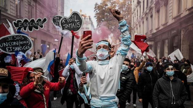 A man gestures while taking a selfie during a protest against the restrictions imposed by the government in wake of the coronavirus pandemic in Lyon, France on November 23. (Jeff Pachoud / AFP) 