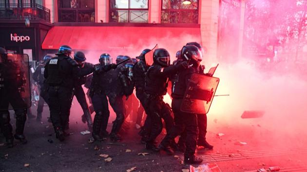 French riot police officers take cover during the protest in Paris on November 28. Tensions intensified in France after a black music producer Michel Zecler was beaten up by police officers in Paris last weekend. (Alain Jocard / AFP) French riot police officers take cover during the protest in Paris on November 28. Tensions intensified in France after a black music producer Michel Zecler was beaten up by police officers in Paris last weekend. (Alain Jocard / AFP)