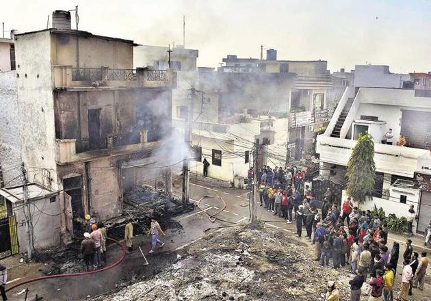 Ludhiana Residents watch as firefighters extinguish the fire that broke out in a furniture workshop located amid houses in Haibowal. Ludhiana, on Sunday afternoon. Workers escaped injuries by rushing out to safety in time. (Harsimar Pal Singh/HT)