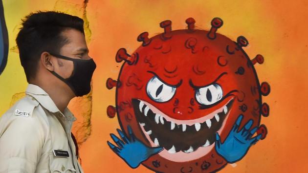 A DCD volunteer wearing face mask walks past a mural on novel coronavirus and protective measures, in New Delhi, on November 24.(PTI File Photo)