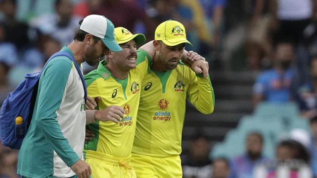 Australia's David Warner, centre, is assisted from the field after injuring himself while fielding during the one day international cricket match between India and Australia at the Sydney Cricket Ground in Sydney, Australia, Sunday, Nov. 29, 2020. (AP Photo/Rick Rycroft)(AP)