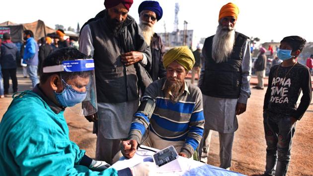 A medical professional checks on a protesting farmer at a medical camp set up near the protest site in Singhu border, New Delhi on November 30. (Biplov Bhuyan / HT Photo)