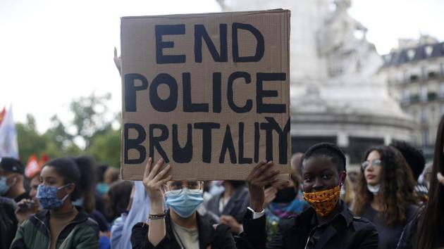 In this June 9, 2020 file photo, demonstrators hold a placard during a rally against racism in Paris after George Floyd's death in the U.S. As videos helped reveal many cases of police brutality, French civil rights activists voiced fears that a new security law would threaten efforts by people from minorities and poor neighborhoods to document incidents involving law enforcement officers. French President Emmanuel Macron's government is pushing a new security bill that would notably make it illegal to publish images of officers with intent to cause them harm. (AP) In this June 9, 2020 file photo, demonstrators hold a placard during a rally against racism in Paris after George Floyd's death in the U.S. As videos helped reveal many cases of police brutality, French civil rights activists voiced fears that a new security law would threaten efforts by people from minorities and poor neighborhoods to document incidents involving law enforcement officers. French President Emmanuel Macron's government is pushing a new security bill that would notably make it illegal to publish images of officers with intent to cause them harm. (AP)
