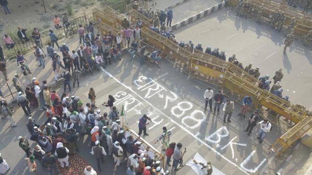 Police personnel stand behind barriers as a symbolic “Section 288” to counter the police’s Section 144 is marked on the protest site by farmers at Ghazipur border near Delhi on November 30. The ongoing protests by thousands of farmers against the new farm reform laws has entered its sixth day on December 1, with the protestors having threatening to block all five entry points to the national capital, HT reported. (Sakib Ali / HT Photo)