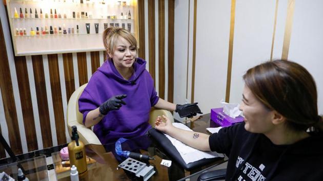 Tattoo artist Soraya Shahidy, speaks with a customers at her beauty salon in Kabul, Afghanistan.(REUTERS)