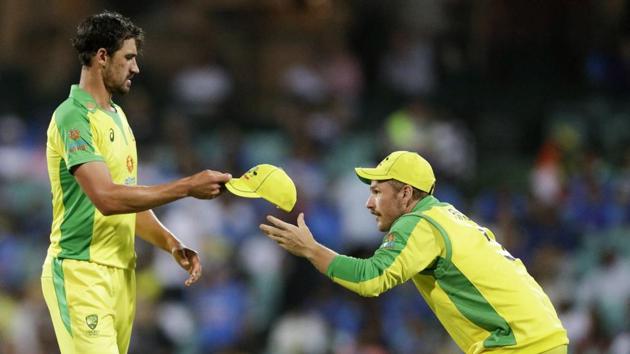 Australia's Mitchell Starc, left, hands his cap to captain Aaron Finch as he prepares to bowl during the one day international cricket match between India and Australia at the Sydney Cricket Ground in Sydney, Australia, Sunday, Nov. 29, 2020. (AP Photo/Rick Rycroft)(AP)