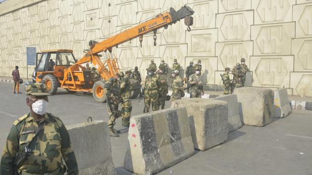 Police personnel are seen next to concrete barricades installed to stop any vehicular movement by the protesting farmers at Ghazipur border on November 30. The barriers were placed after farmer leaders said they will block more highways connecting Delhi apart from Singhu and Tikri borders. (Sakib Ali / HT Photo)