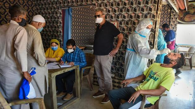 A health worker collects a nasal sample for Covid-19, outside a bus terminal in Srinagar. (PTI) A health worker collects a nasal sample for Covid-19, outside a bus terminal in Srinagar. (PTI)