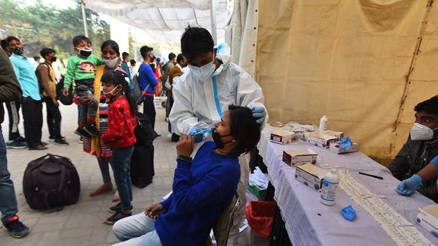 A healthcare worker collects swab sample from a passenger to test for Covid-19 infection, near Anand Vihar bus terminal, in New Delhi on Tuesday.(Raj K Raj/HT Photo)