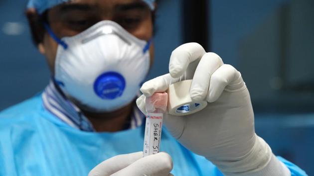 A doctors seals a vial containing a swab with tape while conducting Covid-19 reverse transcription polymerase chain reaction tests (RT-PCR) on Delhi Municipal Corp. workers at the Civic Center building in New Delhi.(Bloomberg) A doctors seals a vial containing a swab with tape while conducting Covid-19 reverse transcription polymerase chain reaction tests (RT-PCR) on Delhi Municipal Corp. workers at the Civic Center building in New Delhi.(Bloomberg)