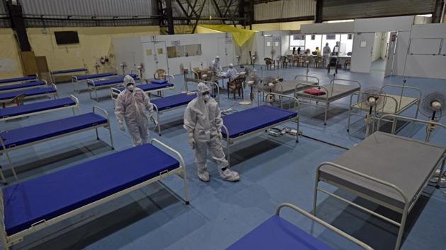 Health workers walk past beds at a new post Covid-19 OPD Center run by the BMC at NESCO in Mumbai on November 30. Suresh Kakani, additional municipal commissioner of BMC, told HT, “The testing went down in first half of November, but has improved in the second half. The next few weeks are crucial as we aim to maximise testing by setting up 244 testing centres and taking other initiatives to test citizens.” (Satyabrata Tripathy / HT Photo)