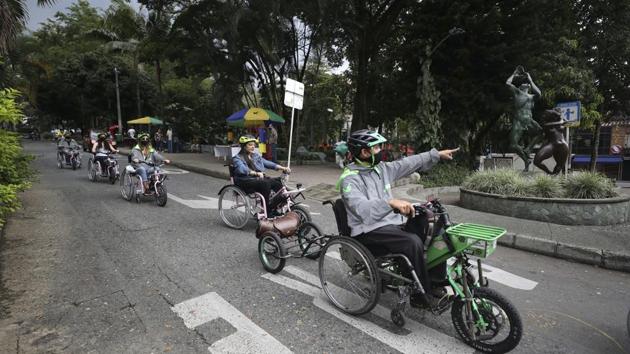 Wilson Guzman, a tour guide, right, leads an electric wheelchair tour in Medellin, Colombia, Wednesday, Nov. 18, 2020. ?For the equivalent of $25, both people who can and can't walk can get on the electric wheelchairs and take the three-hour tour of the city’s riverside parks, which includes stops at a coffee shop and a bar that does beer tasting. (AP)