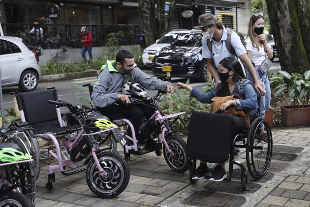 Martin Londoño, left, owner of MATT, an electric wheelchair tour company, greets a client in Medellin, Colombia, Wednesday, Nov. 18, 2020. (AP) Martin Londoño, left, owner of MATT, an electric wheelchair tour company, greets a client in Medellin, Colombia, Wednesday, Nov. 18, 2020. (AP)