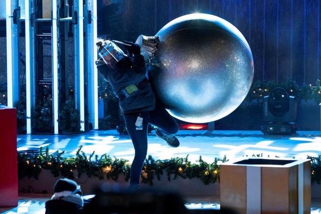 A worker wearing a face protection balances with a decoration ball as she sets up the stage during lighting of the Christmas tree at Rockefeller Center amid COVID-19 restrictions in New York City, New York, U.S., December 2, 2020. (REUTERS) A worker wearing a face protection balances with a decoration ball as she sets up the stage during lighting of the Christmas tree at Rockefeller Center amid COVID-19 restrictions in New York City, New York, U.S., December 2, 2020. (REUTERS)