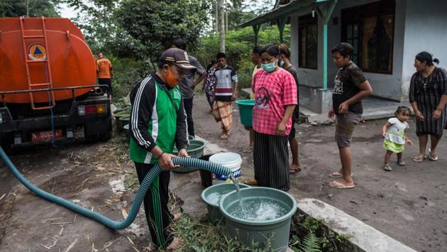 Villagers collect clean water supplied by the local government following the eruption of Mount Semeru volcano in Lumajang, East Java province, Indonesia on December 3. (Juni Kriswanto / AFP)