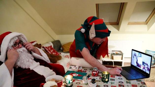 An assistant helps Pal Pillmayer, dressed as Santa Claus, as he prepares to interact with children by video chat.(REUTERS)
