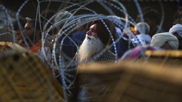 An Indian farmer looks through the barbed wires put up by the police at the site of a protest on a highway at the Delhi-Haryana state border. (AP) An Indian farmer looks through the barbed wires put up by the police at the site of a protest on a highway at the Delhi-Haryana state border. (AP)