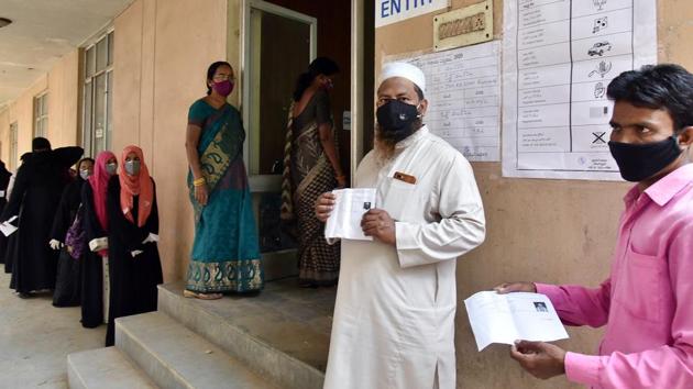 People show their voter ID slips as they stand in a queue to vote for the GHMC polls 2020, in Hyderabad on Thursday.(ANI Photo)