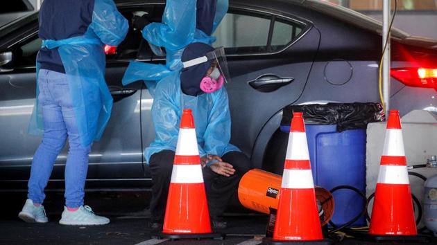 A health care worker warms himself on a portable heater as others collect samples for coronavirus tests at a drive-through testing centre in Paramus, New Jersey on December 3. The spiraling pandemic has prompted state and national political leaders to order increasingly aggressive countermeasures while Americans wait for governmental approval of vaccines developed by drug companies Pfizer Inc and Moderna. (Brendan McDermid / REUTERS) A health care worker warms himself on a portable heater as others collect samples for coronavirus tests at a drive-through testing centre in Paramus, New Jersey on December 3. The spiraling pandemic has prompted state and national political leaders to order increasingly aggressive countermeasures while Americans wait for governmental approval of vaccines developed by drug companies Pfizer Inc and Moderna. (Brendan McDermid / REUTERS)