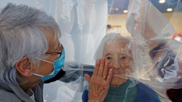 Family members stand on either side of the plastic sheet to interact.(REUTERS) Family members stand on either side of the plastic sheet to interact.(REUTERS)