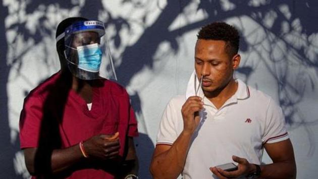 A healthcare worker stands by as a man takes a test for Covid-19 in Staten Island, New York. (REUTERS) A healthcare worker stands by as a man takes a test for Covid-19 in Staten Island, New York. (REUTERS)