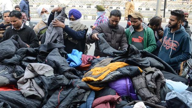 People browse through used winter clothes at a roadside stall in Amritsar on December 6. India’s Covid-19 tally had crossed the 9 million mark on November 20. Cases in the country have been on a decline since mid-September but caution prevails for spikes in cases due to the advent of winter. (Narinder Nanu / AFP) People browse through used winter clothes at a roadside stall in Amritsar on December 6. India’s Covid-19 tally had crossed the 9 million mark on November 20. Cases in the country have been on a decline since mid-September but caution prevails for spikes in cases due to the advent of winter. (Narinder Nanu / AFP)
