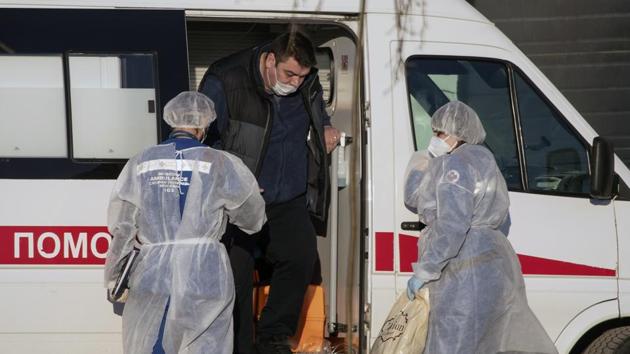 Medical workers tend to a man, suspected of having coronavirus, at the hospital for coronavirus patients in Kommunarka outside Moscow on December 5. The age for those receiving shots is capped at 60. People with certain underlying health conditions, pregnant women and those who have had a respiratory illness for the past two weeks are barred from vaccination. (Pavel Golovkin / AP) Medical workers tend to a man, suspected of having coronavirus, at the hospital for coronavirus patients in Kommunarka outside Moscow on December 5. The age for those receiving shots is capped at 60. People with certain underlying health conditions, pregnant women and those who have had a respiratory illness for the past two weeks are barred from vaccination. (Pavel Golovkin / AP)