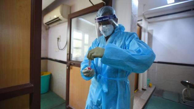 A health worker in PPE kit while collecting swab samples to test for Covid-19 infection, at Bengali Market, in New Delhi. (Amal KS/Hindustan Times) A health worker in PPE kit while collecting swab samples to test for Covid-19 infection, at Bengali Market, in New Delhi. (Amal KS/Hindustan Times)